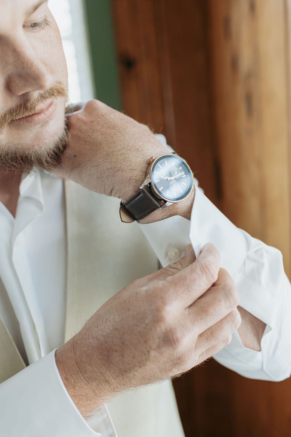 Detail shots of groom adjusting white dress shirt and watch.