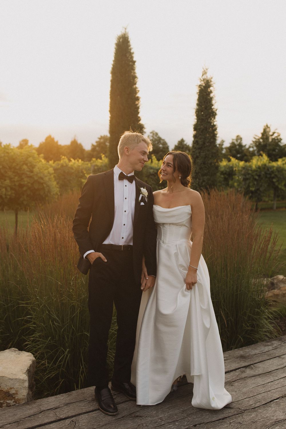 Newlyweds sharing an intimate moment at sunset in a garden setting.