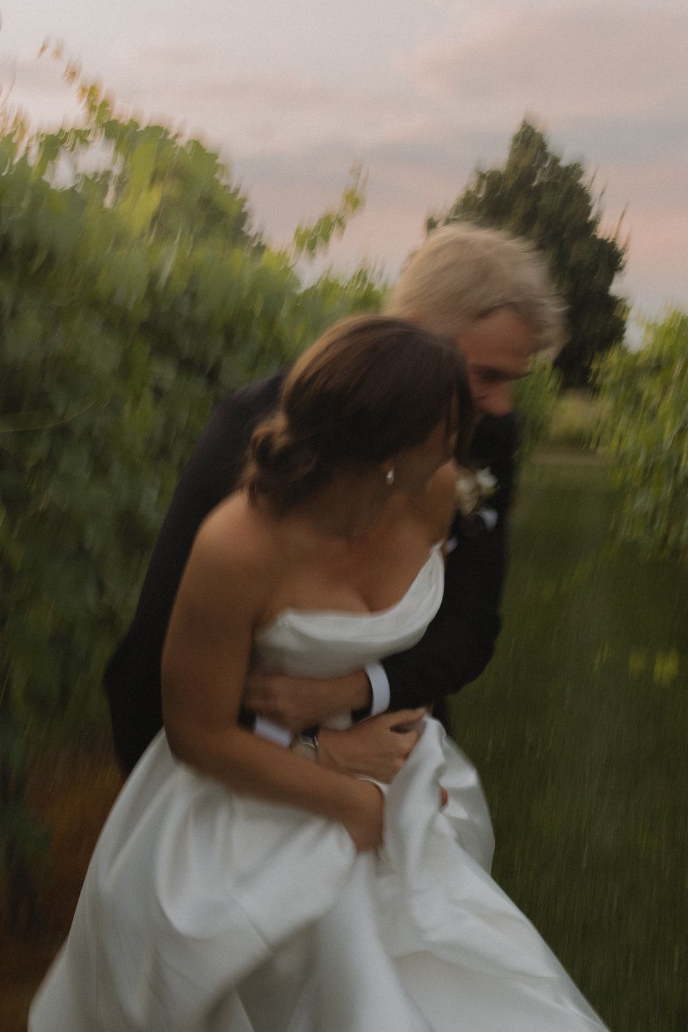 Romantic couple sharing an intimate moment in a vineyard during sunset.