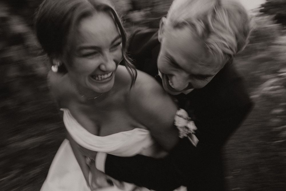 Black and white photo of newlyweds laughing together in a candid moment.