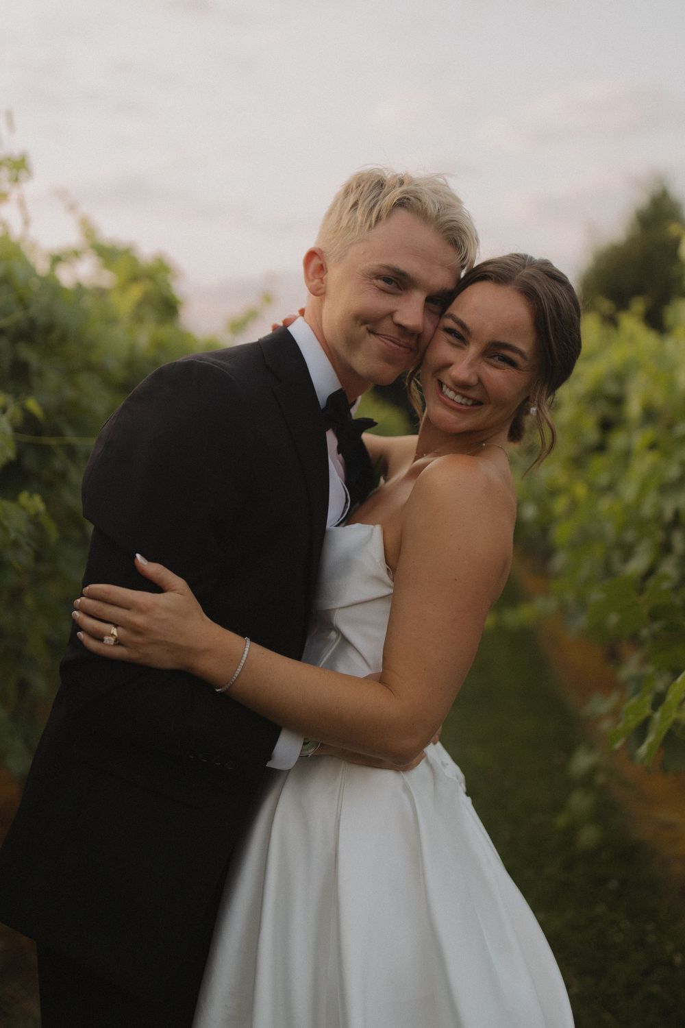 Joyful wedding couple sharing laughter in a vineyard photoshoot.