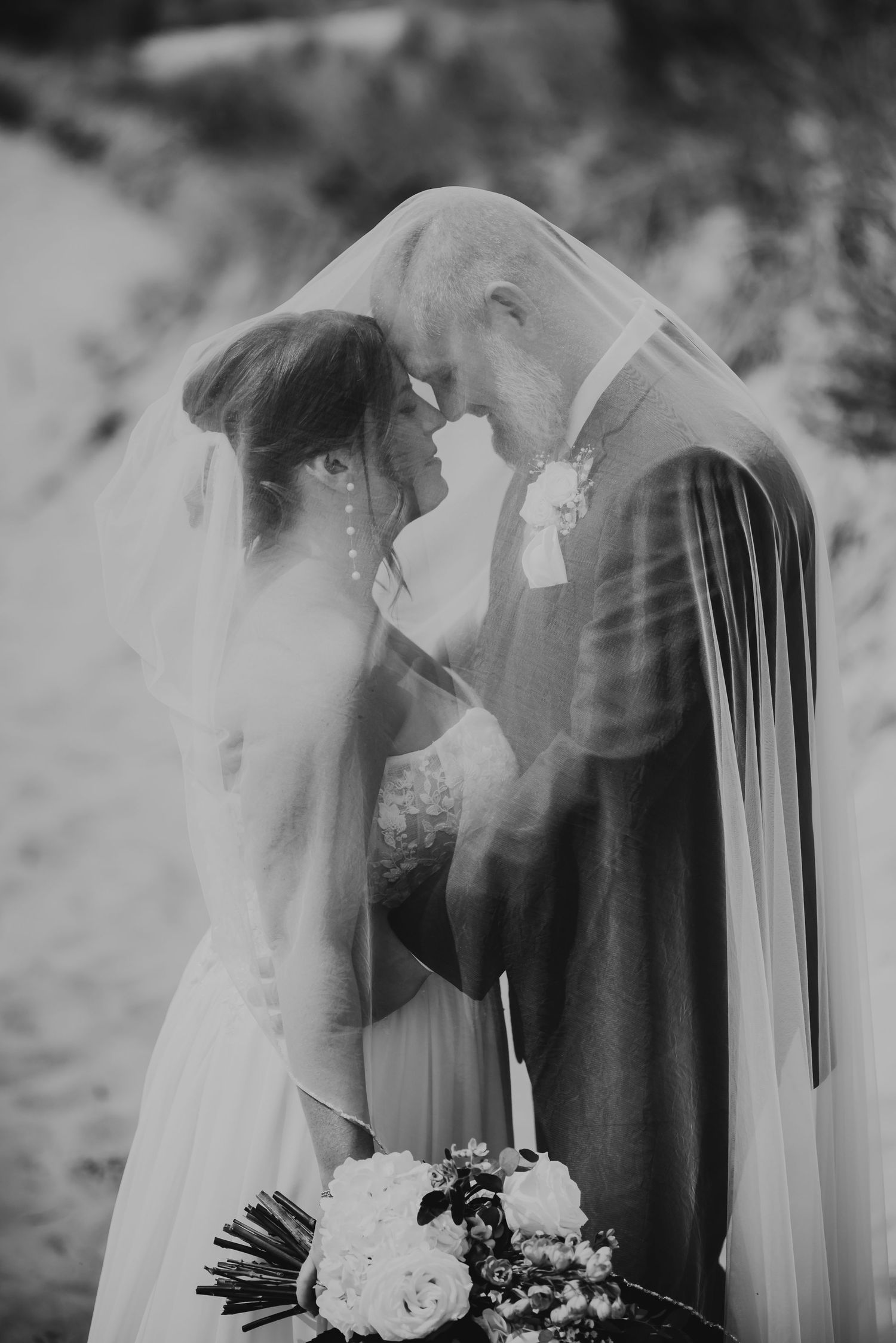 Romantic black and white wedding photos showing couple under flowing veil creating dreamy, intimate moments.