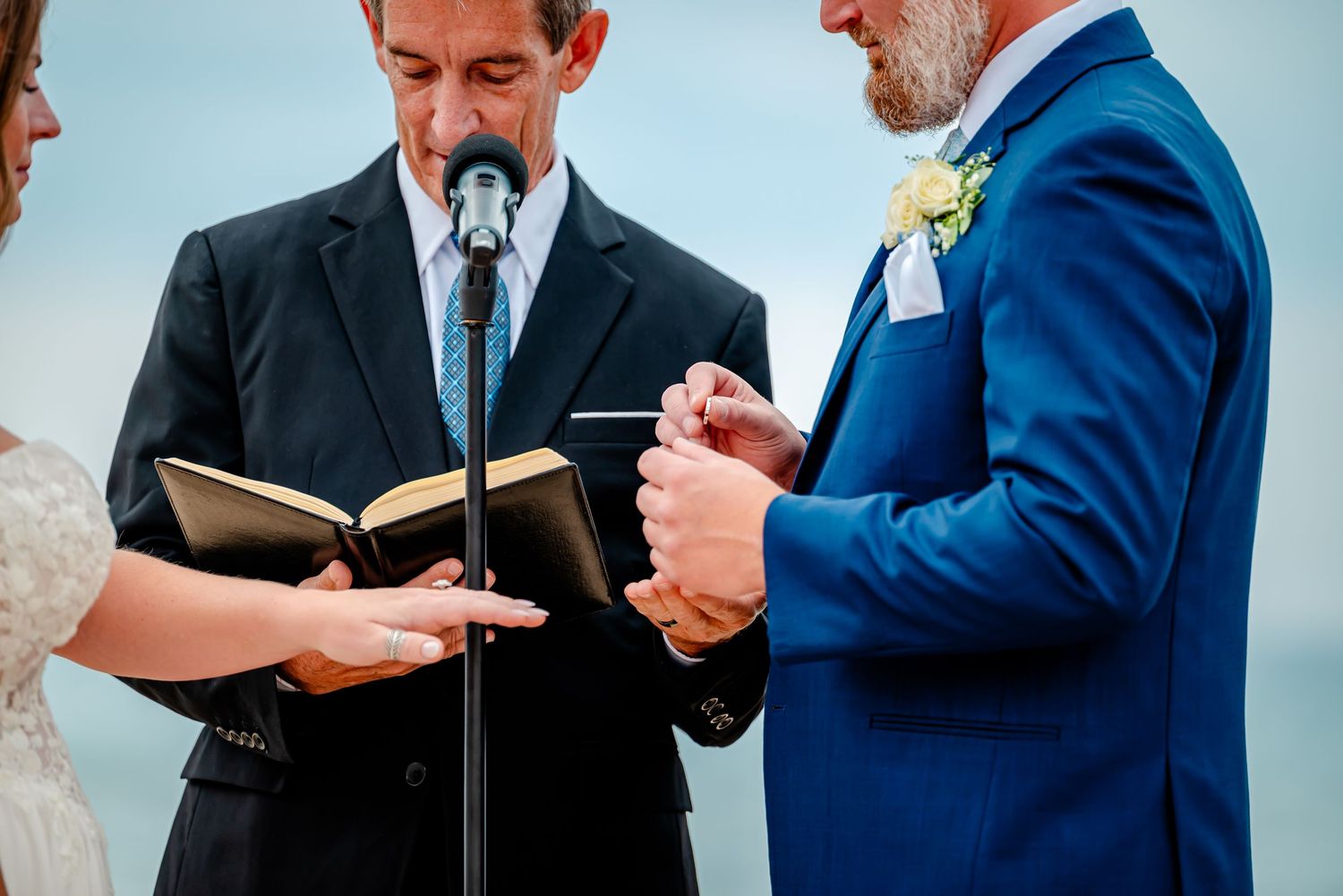 Wedding officiant conducting beach ceremony as couple listens during intimate service.