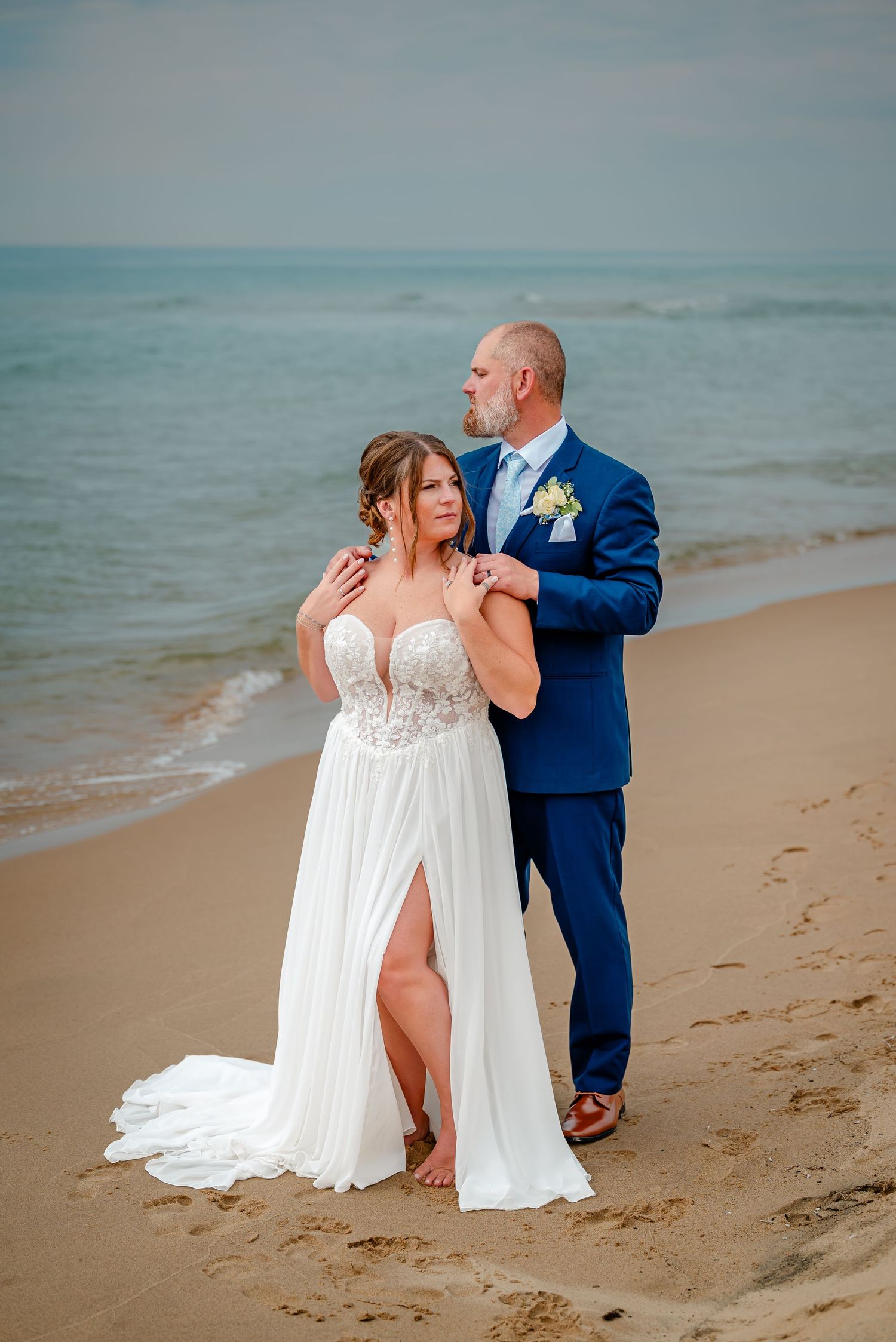 A romantic beach wedding photoshoot with a couple dancing together on the sand at sunset.