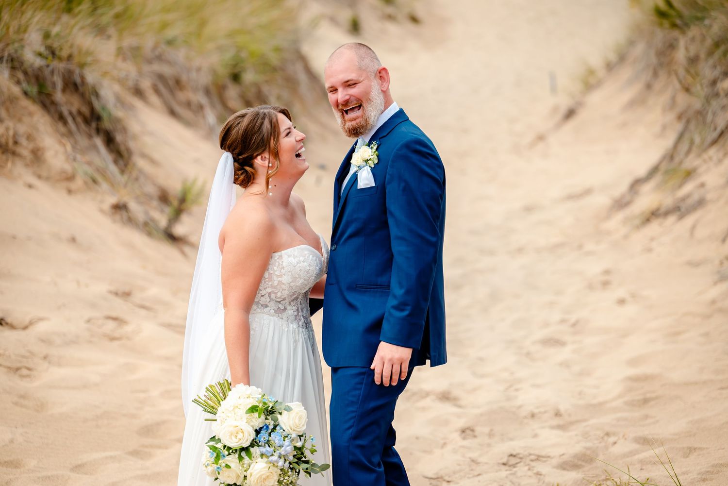 A couple shares a romantic moment on a sandy beach during their wedding photo session.