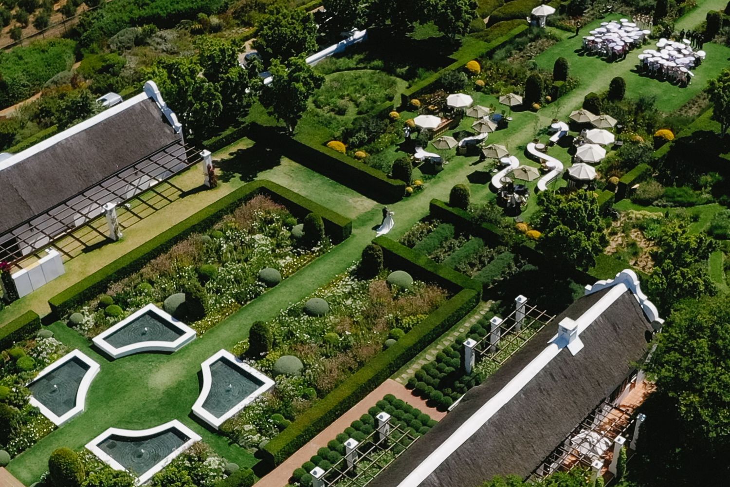 Aerial view of geometric swimming pools and green landscaping in a residential development.