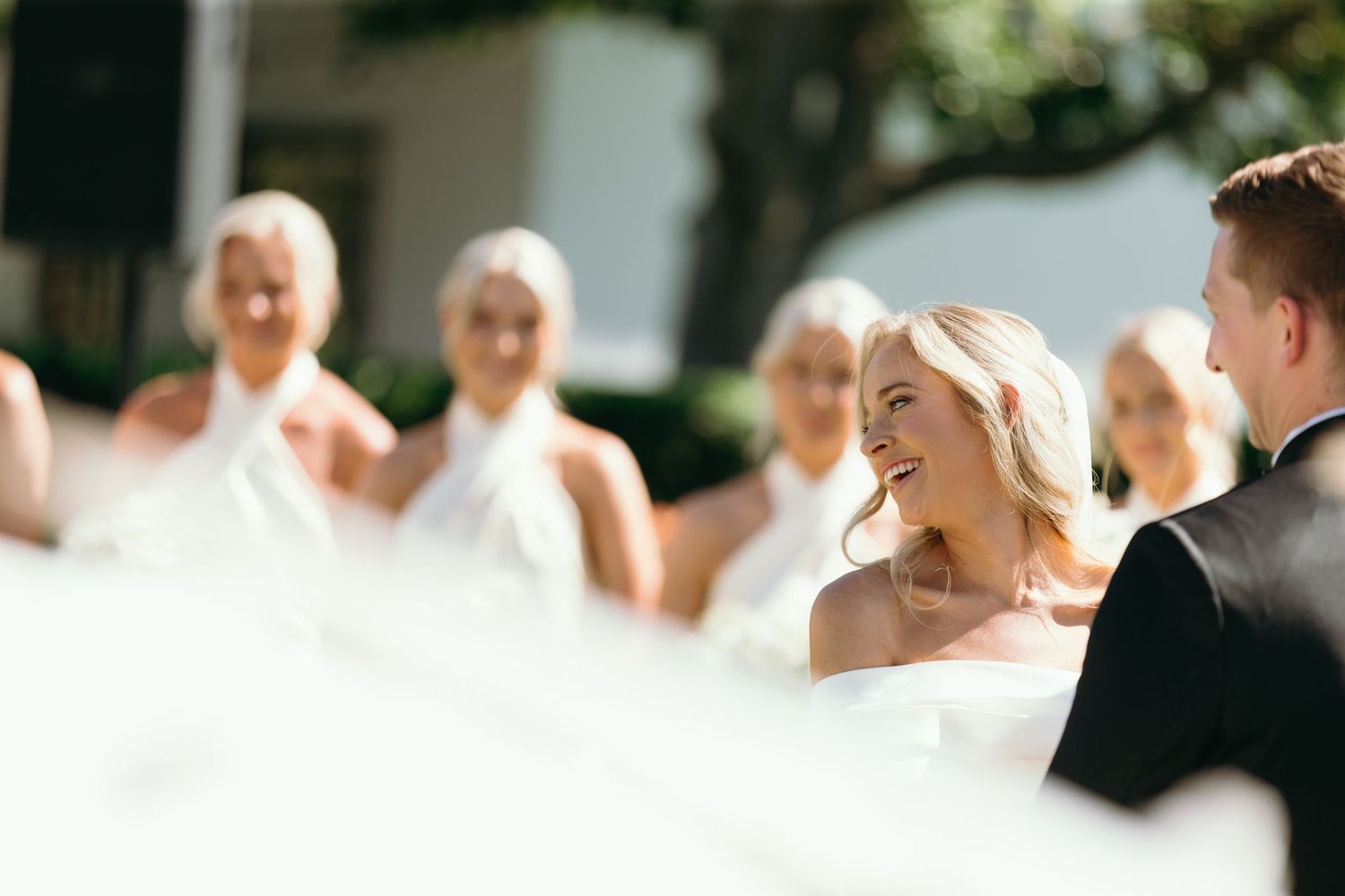 Wedding guests seated at tables outdoors during a sunny reception celebration.