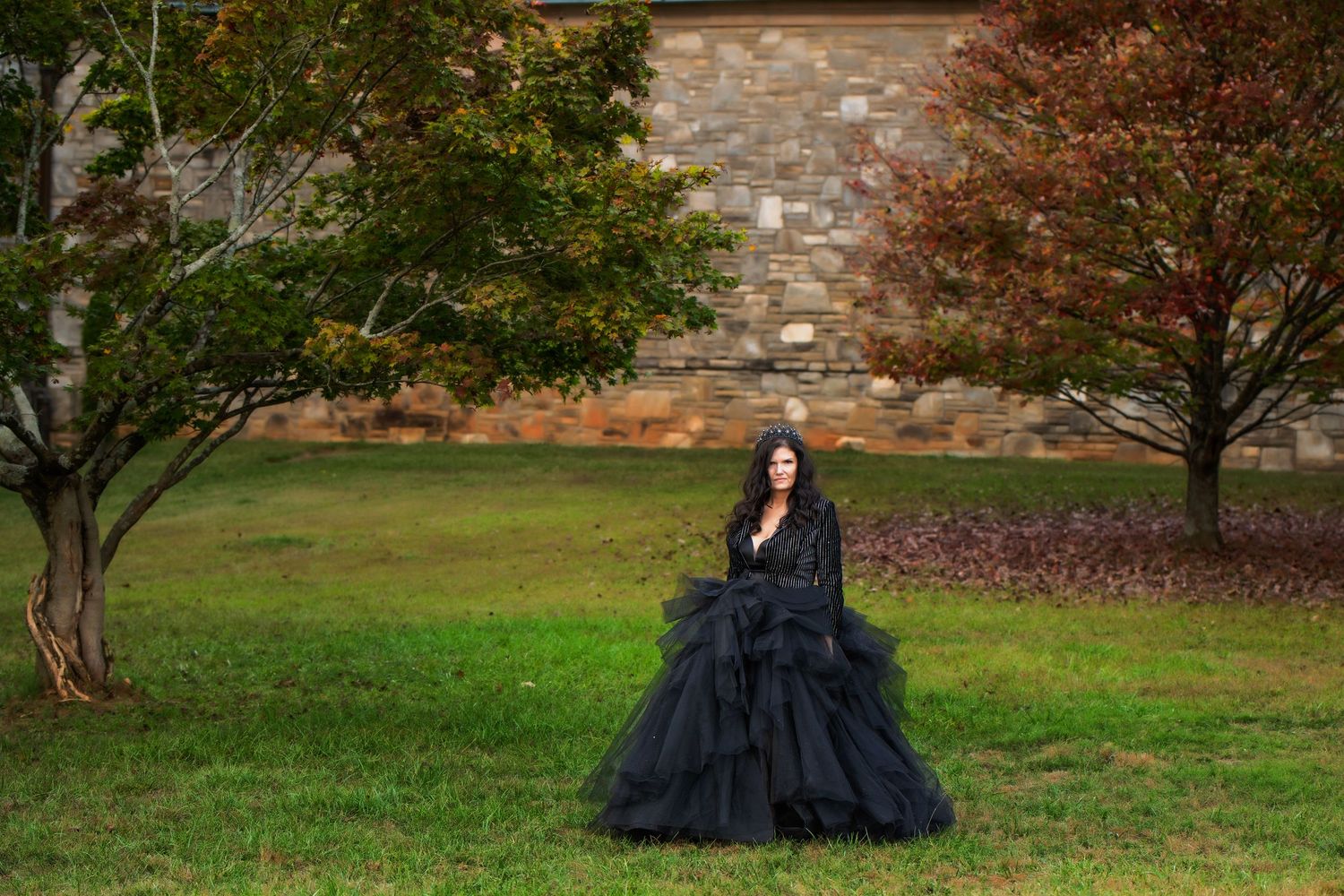 Lady in a large black and gold couture dress standing in the grass in front of trees in a cemetery in Atlanta Georgia