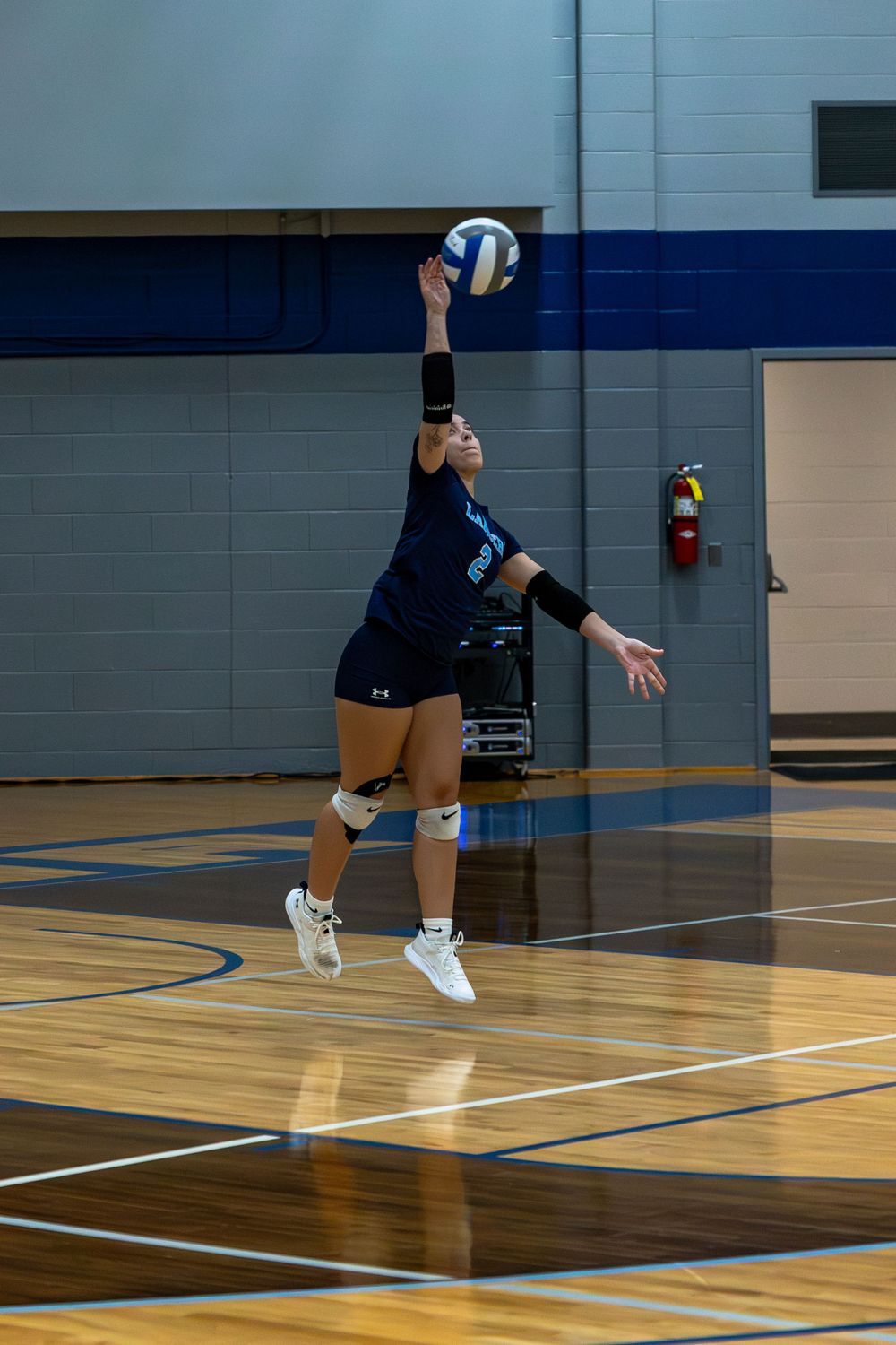 Series of action shots showing volleyball player making diving save on wooden gymnasium court.