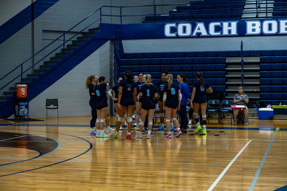 High school volleyball players celebrate together on the court during a match.