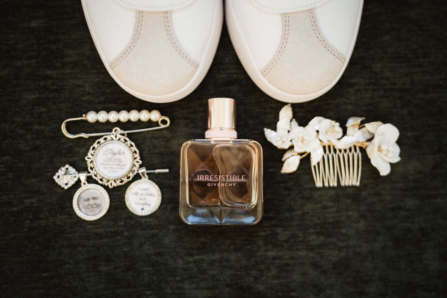 Wedding accessories including white shoes, pearl jewelry, perfume bottle, and hair accessories arranged on dark background.