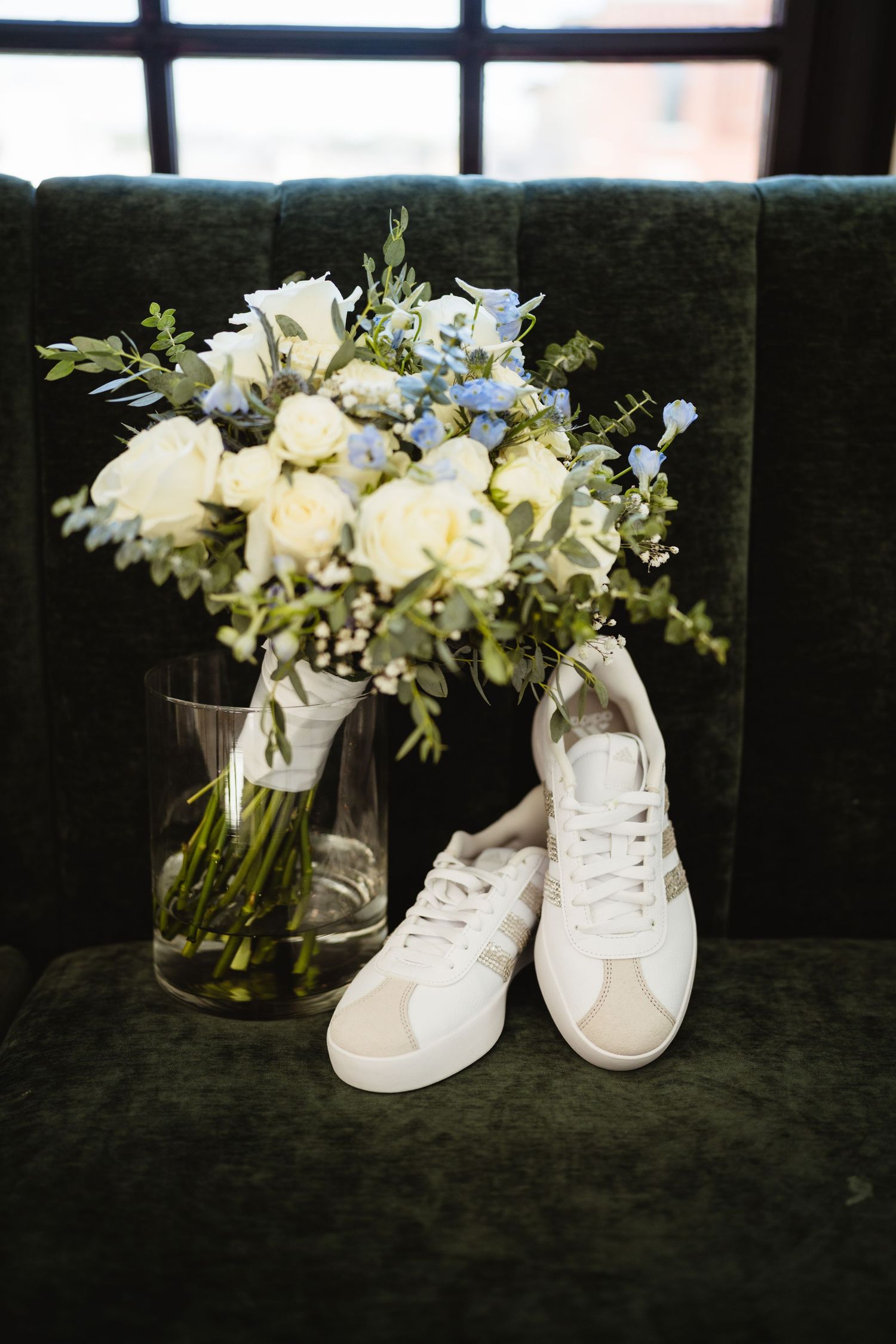 White sneakers decorated with elegant floral arrangements on dark velvet background create artistic wedding detail shots.