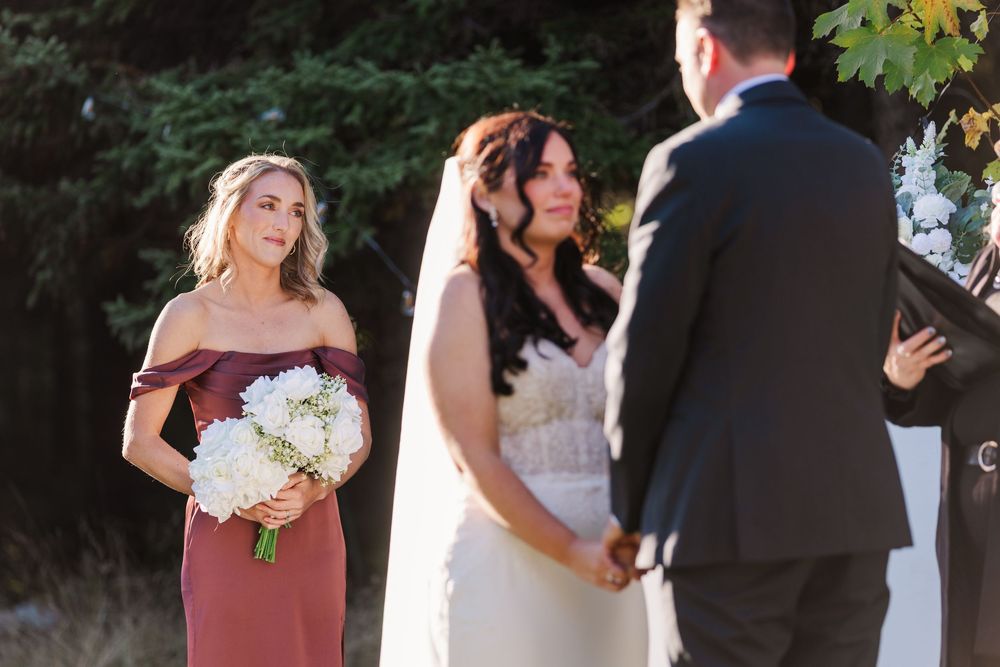 Wedding party members in formal attire gather outdoors for a celebration in natural lighting.