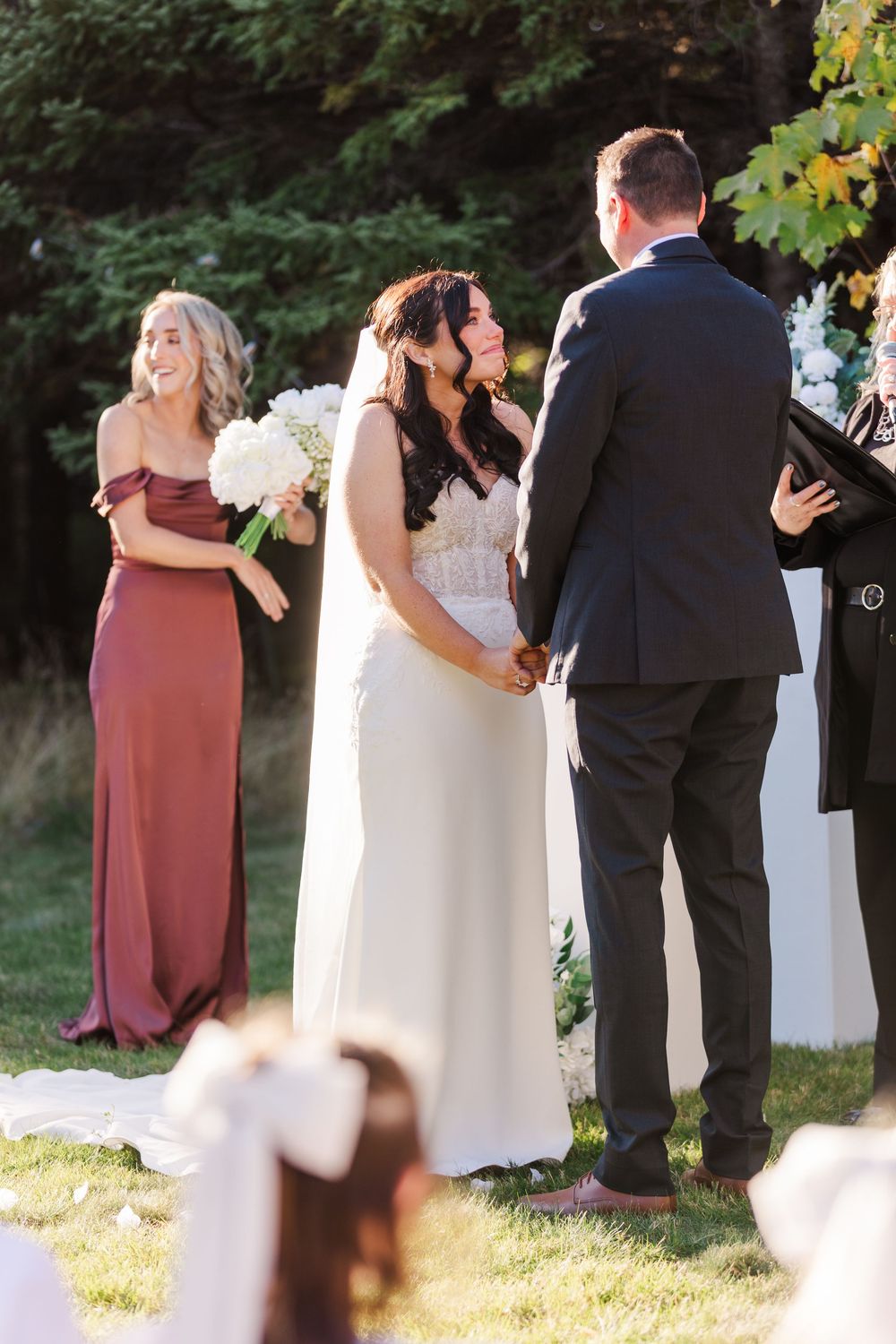 Wedding party stands in a row outdoors during autumn ceremony with warm sunlight filtering through trees.