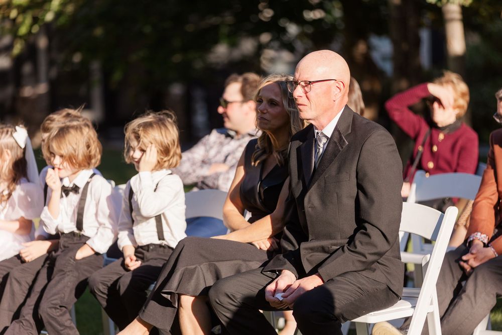 Wedding guests gather outdoors in formal attire during a daytime celebration.