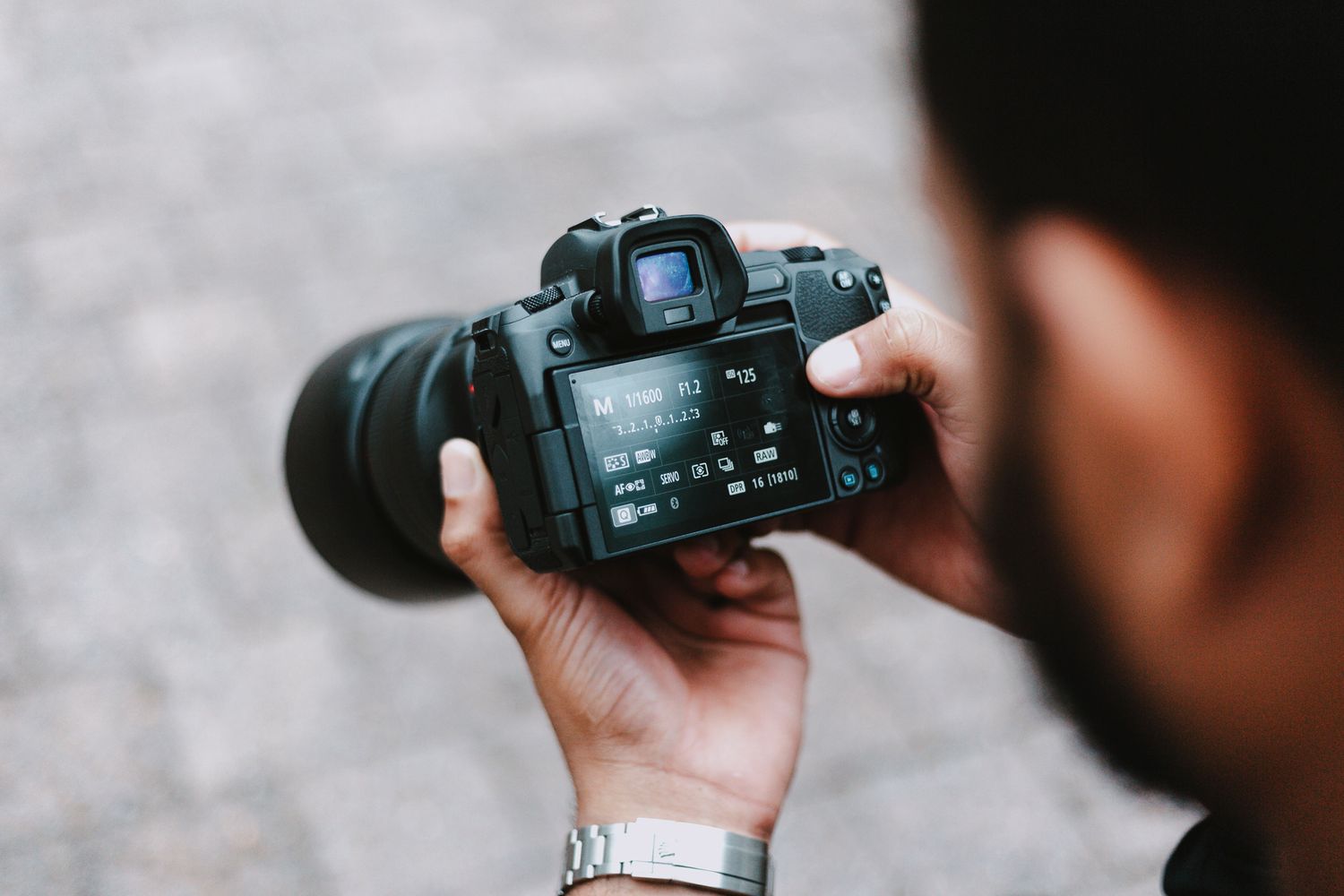 Professional photographer using DSLR camera during outdoor photo session.