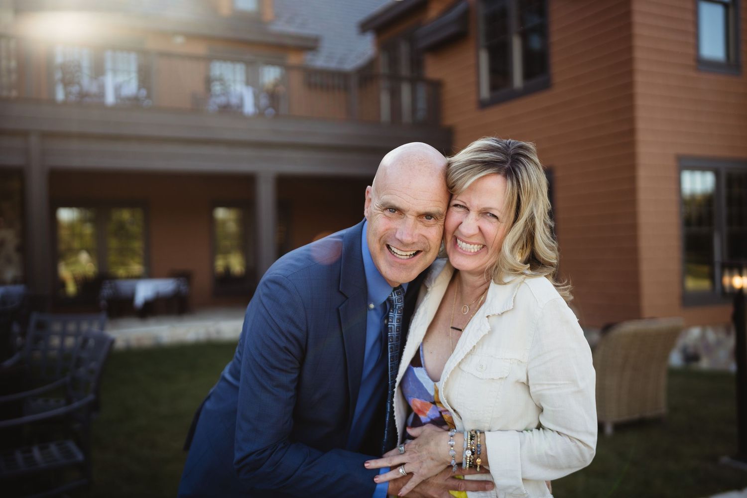 Couple shares intimate moments in front of rustic wooden lodge building at sunset.