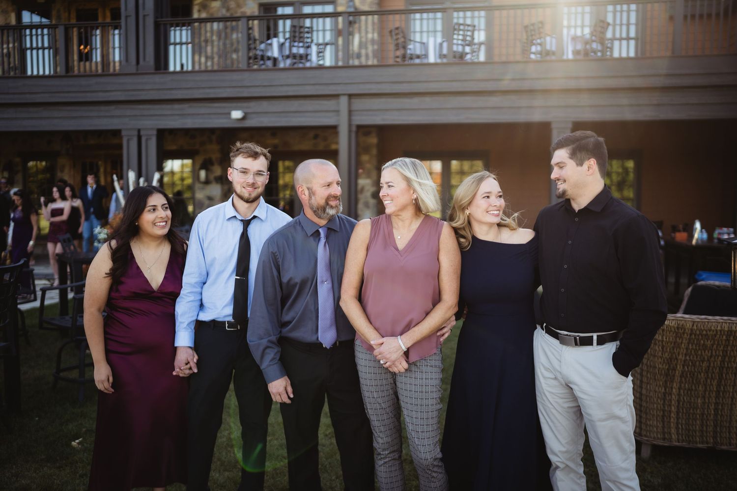 Wedding guests mingle and socialize in an elegant indoor venue with dark wood paneling and warm lighting.