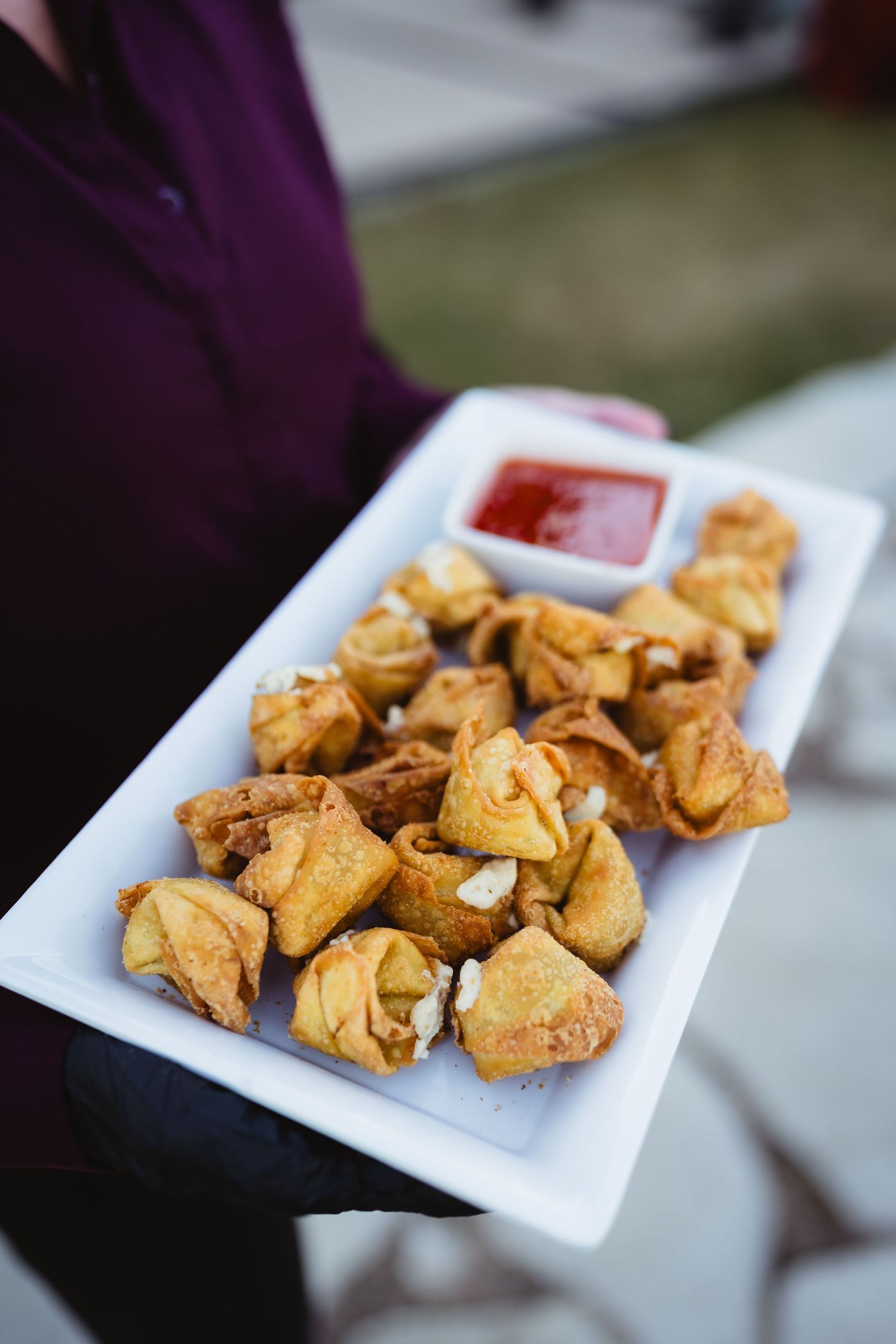 Golden crispy crab rangoon appetizers arranged on a white square plate.
