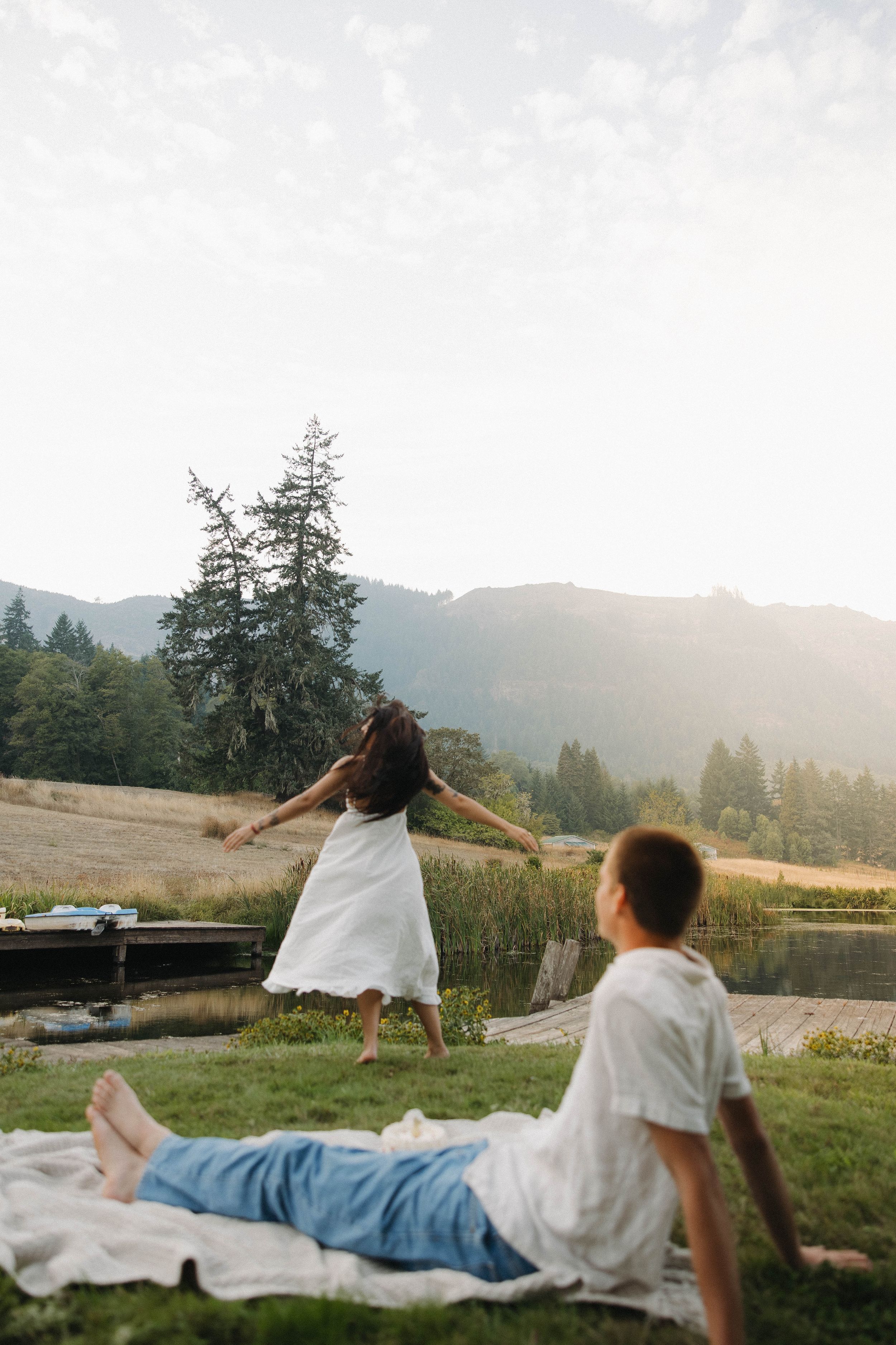 Couple enjoying sunset moment on hillside with mountain views and dramatic lighting.