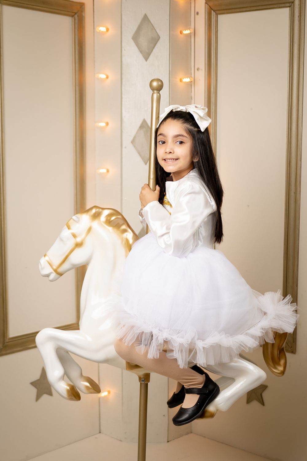A series of dreamy photos showing a person in a white tulle dress posing against a wall with star decorations and lighting.