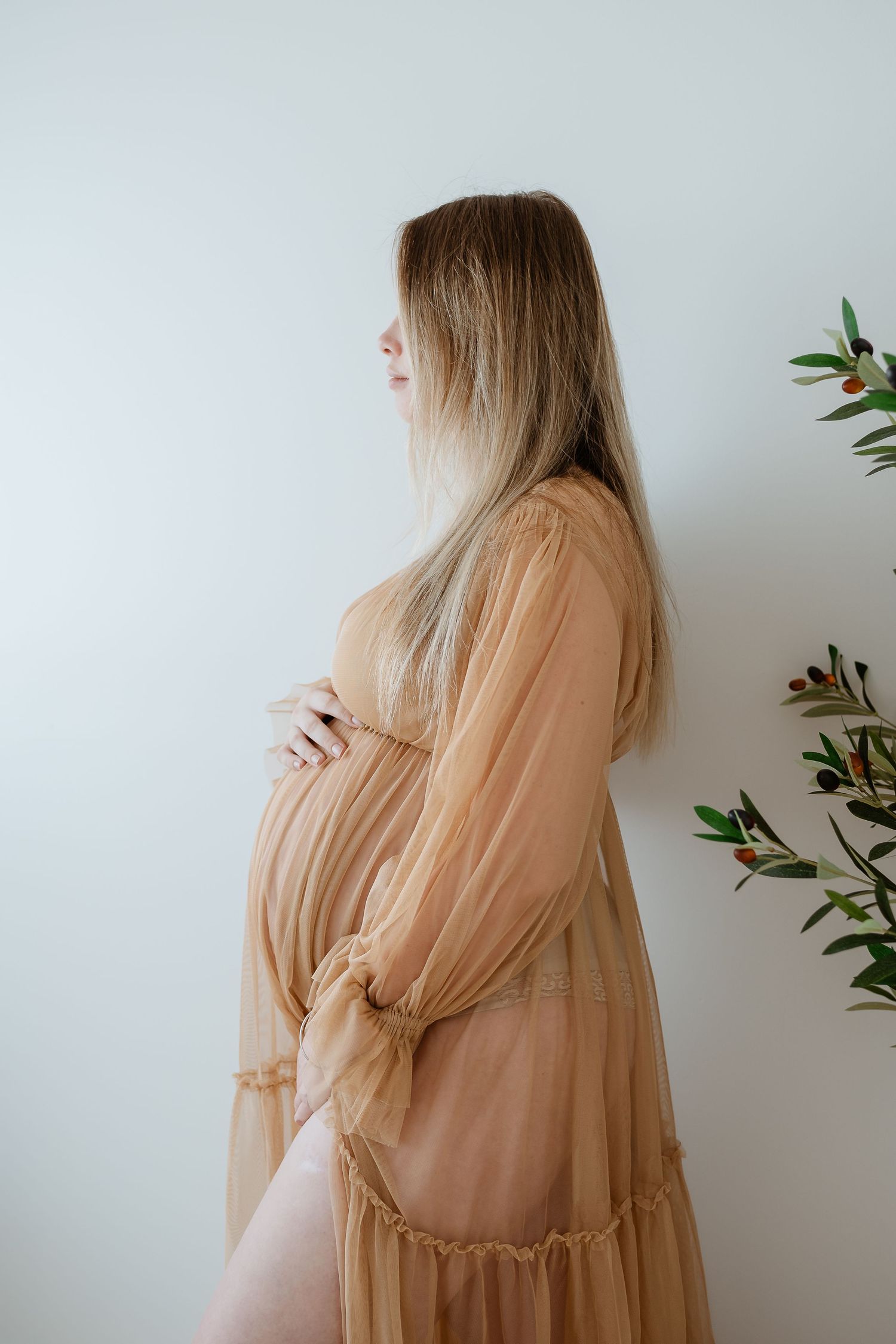 Maternity photo shoot at gladstone beach showing pregnant woman in brown top and white wrap against ocean waves.