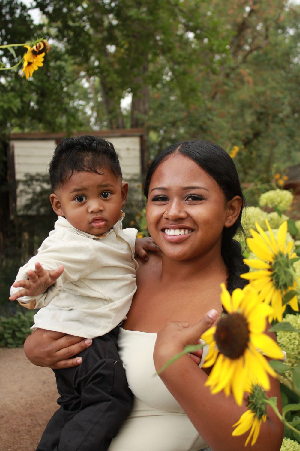 A joyful outdoor family portrait with bright yellow sunflowers in the background on a sunny day.