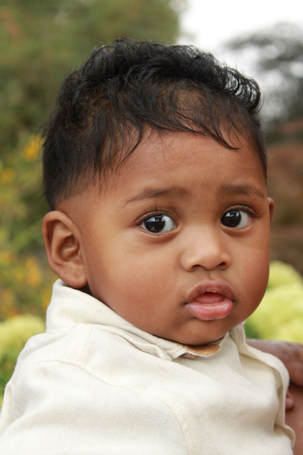 A series of close-up photos showing an adorable baby in white clothing making different facial expressions.