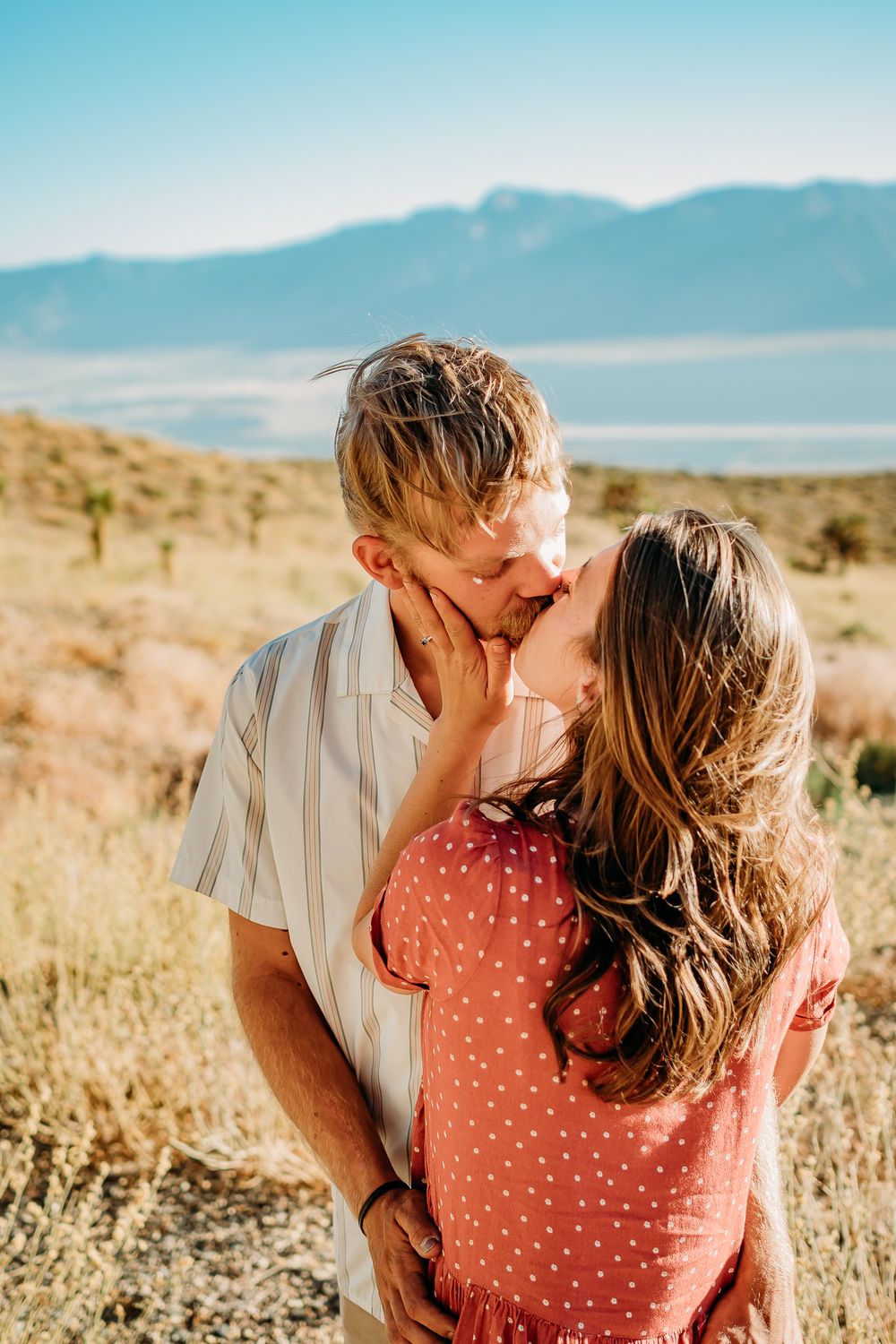 Desert engagement photos with mountains and Joshua trees in background.