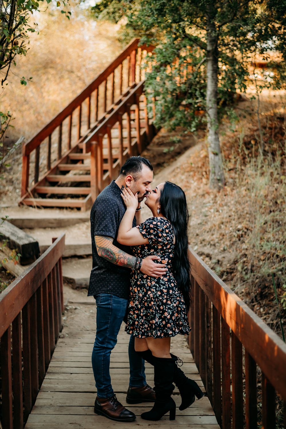 Romantic couple shares intimate moments on wooden stairs surrounded by autumn foliage at sunset.
