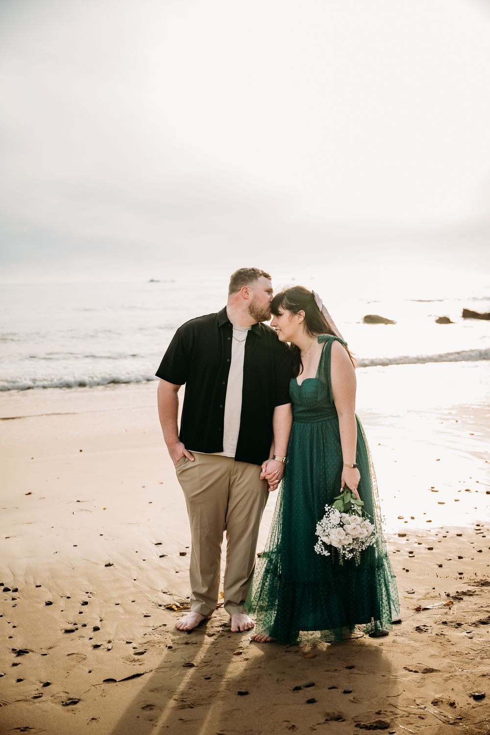 Couple shares quiet moment together sitting on beach at sunset.