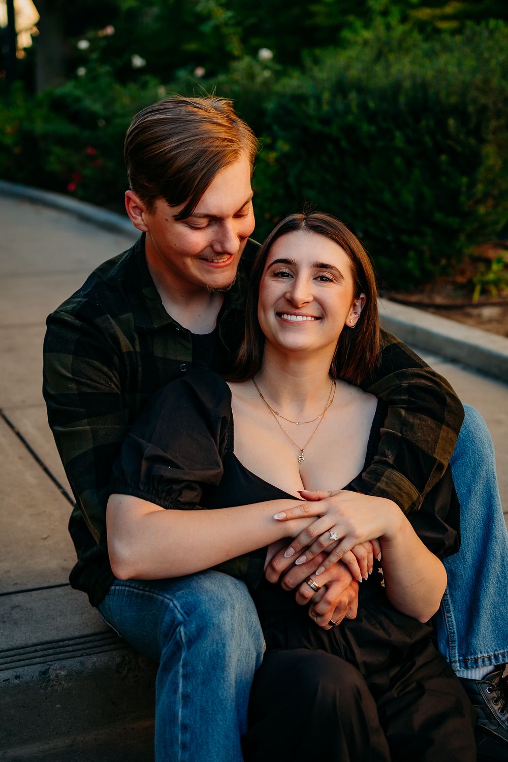 Couple sharing intimate moment on park bench during golden hour engagement session.