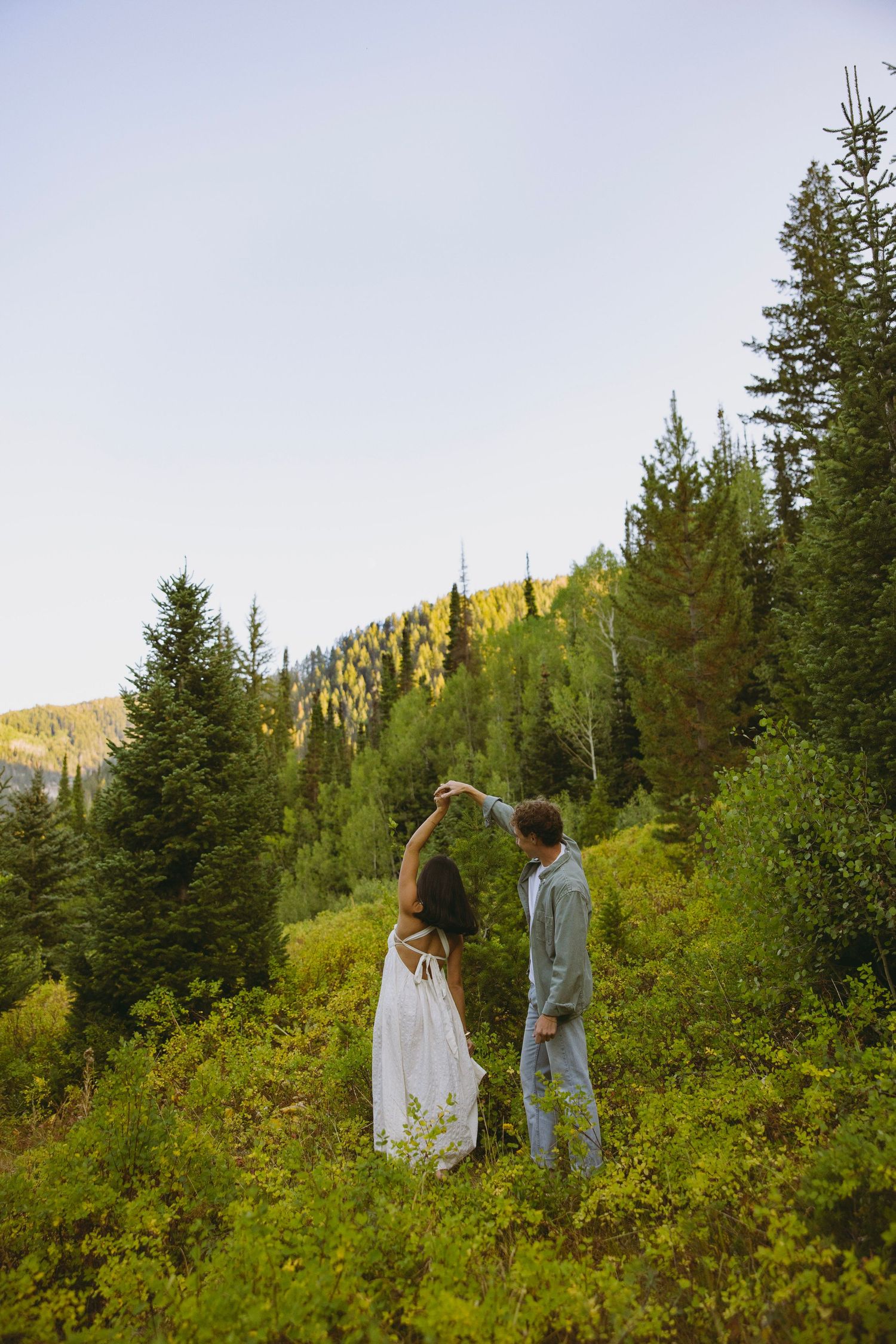A couple shares an intimate moment at the edge of a scenic canyon with red rock formations stretching to the horizon.