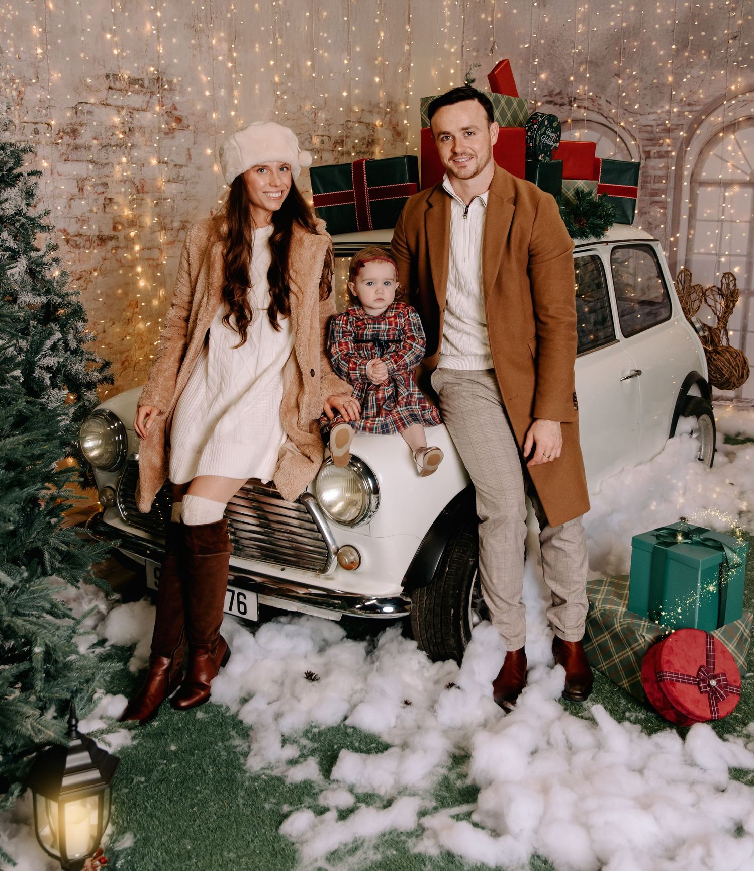 mam & dad with daughter dressed in cream christmas tones sitting on a white old mini cooper car. Christmas photos Westmeath
