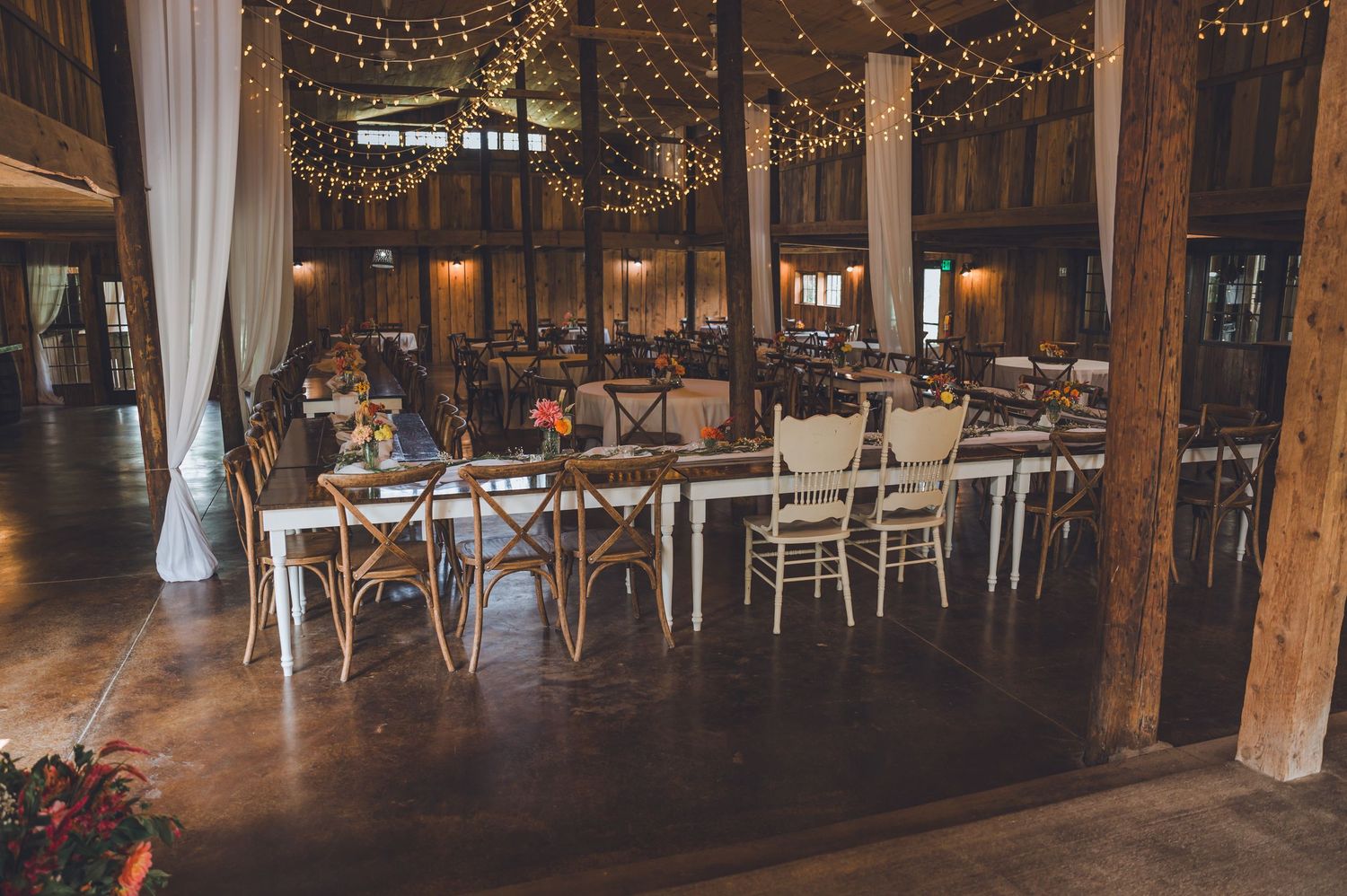 Rustic barn wedding venue interior decorated with twinkling string lights and wooden beams creating a romantic atmosphere.