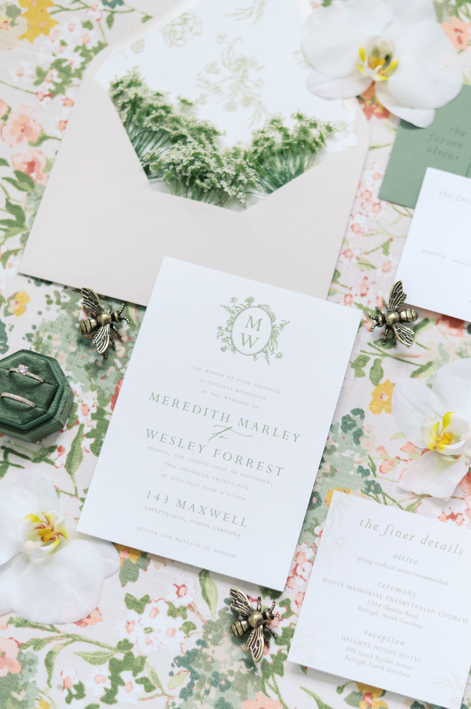 Wedding invitations and stationery with delicate floral designs and green botanical details laid out on a light surface.