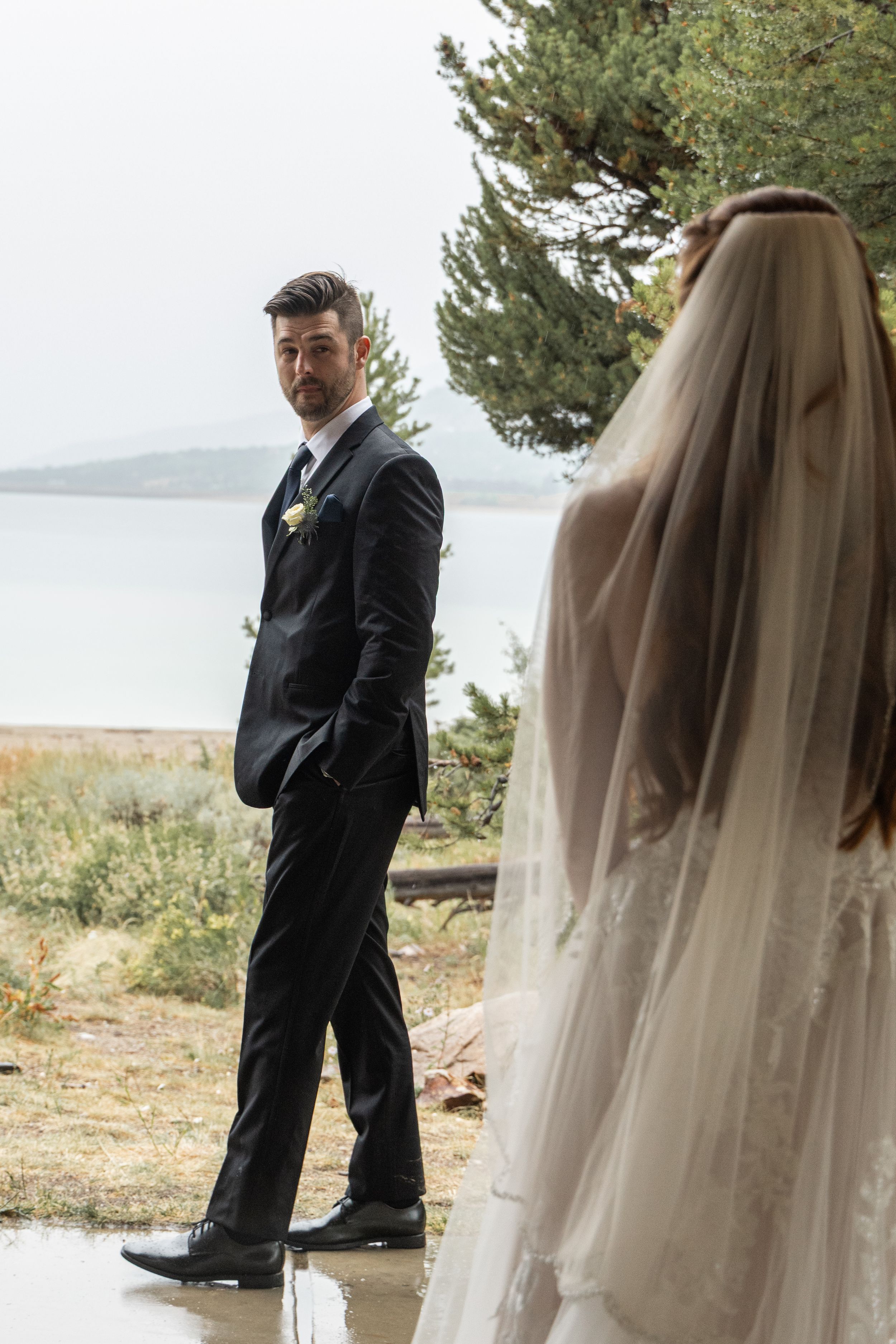 A bride and groom share intimate moments during their outdoor lakeside wedding photoshoot in nature.