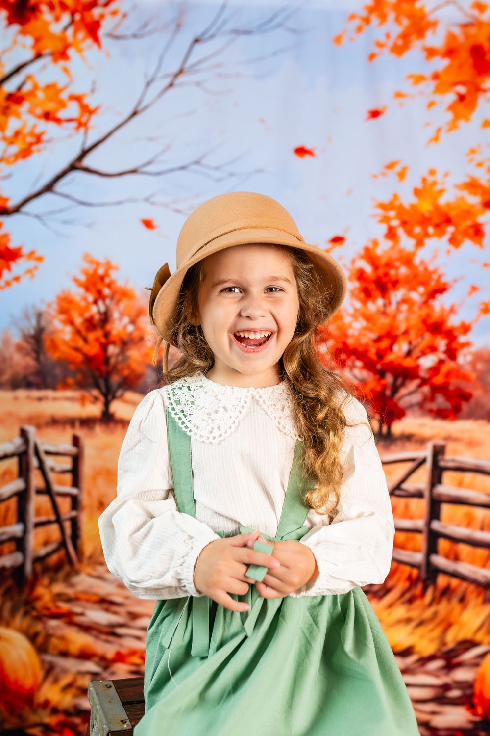 Fall photoshoot setup with bright orange foliage, rustic fence, and mint green dress against autumn scenery.