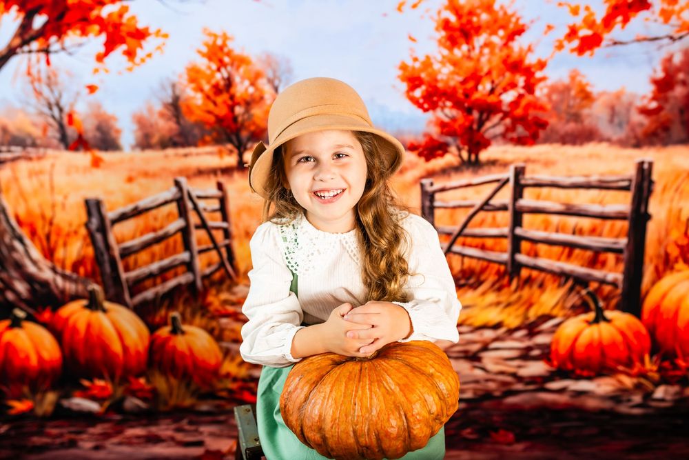 A child in a beige hat poses with a large pumpkin amid an autumn scene with orange maple trees and wooden fences.