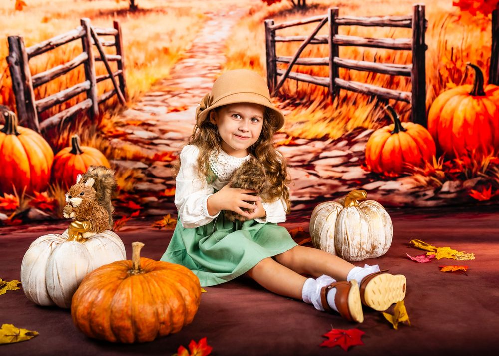 Rustic fall scene with pumpkins, wooden fence, and autumn leaves in warm orange tones.