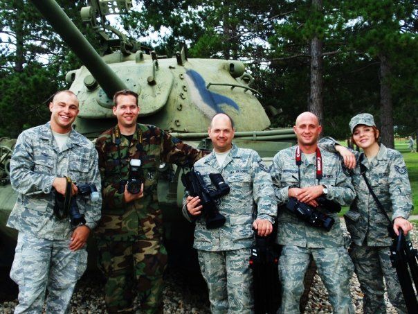 Thornton photographer Ashley bell in camouflage uniforms pose together near military vehicles and equipment with his team.
