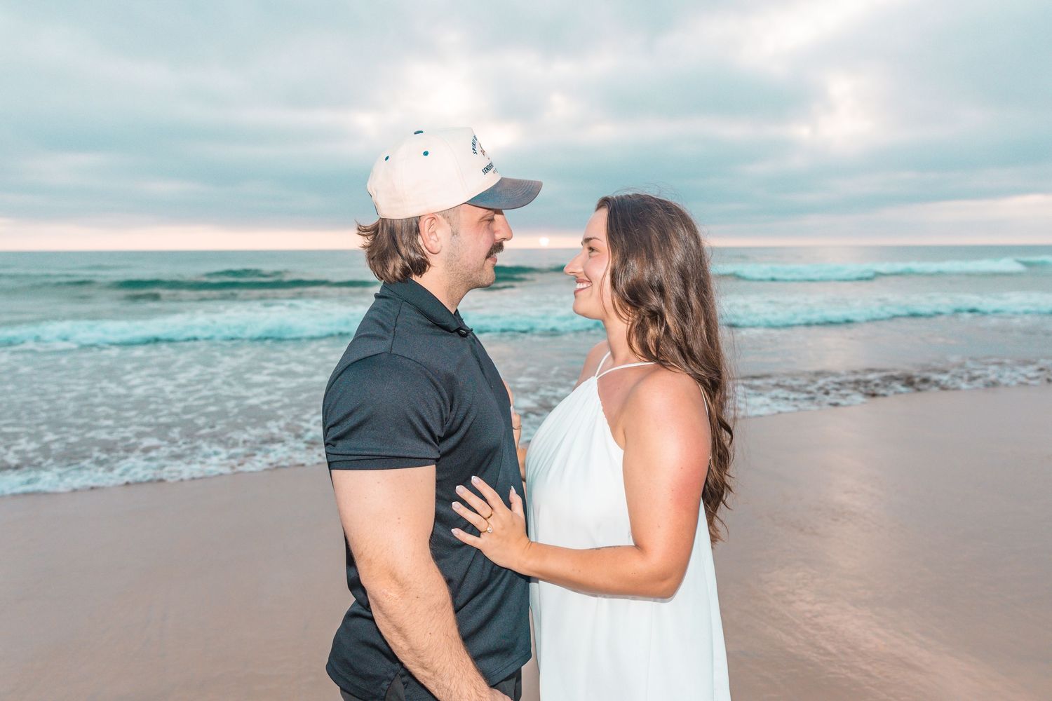 San Diego engagement photography of a newly engaged couple embracing at a harbor marina with boats in the background.