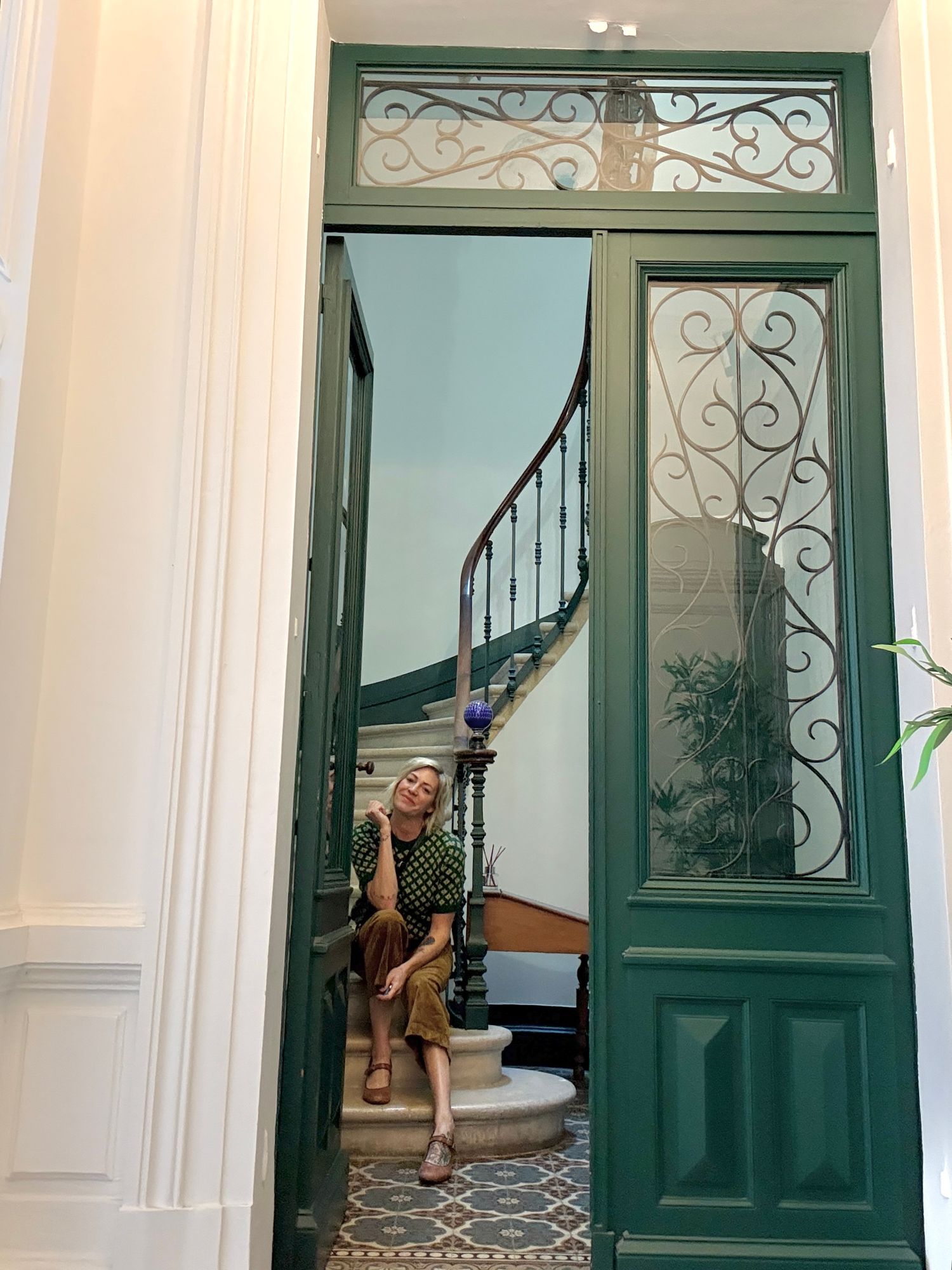 Sequence of green ornate doorway frames with decorative ironwork and white walls.