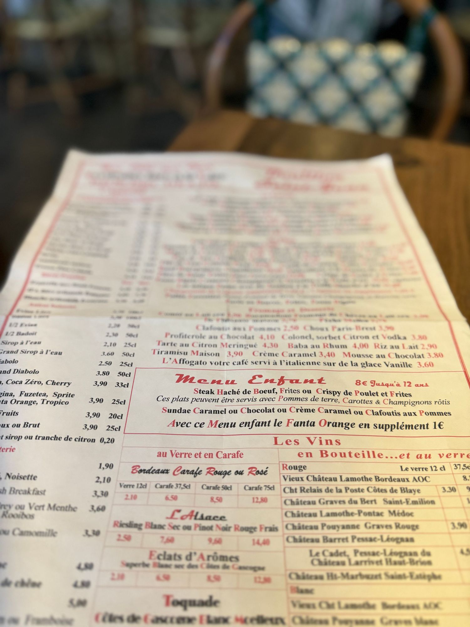 Close-up shots of French restaurant menu with wine list and prices in red text.