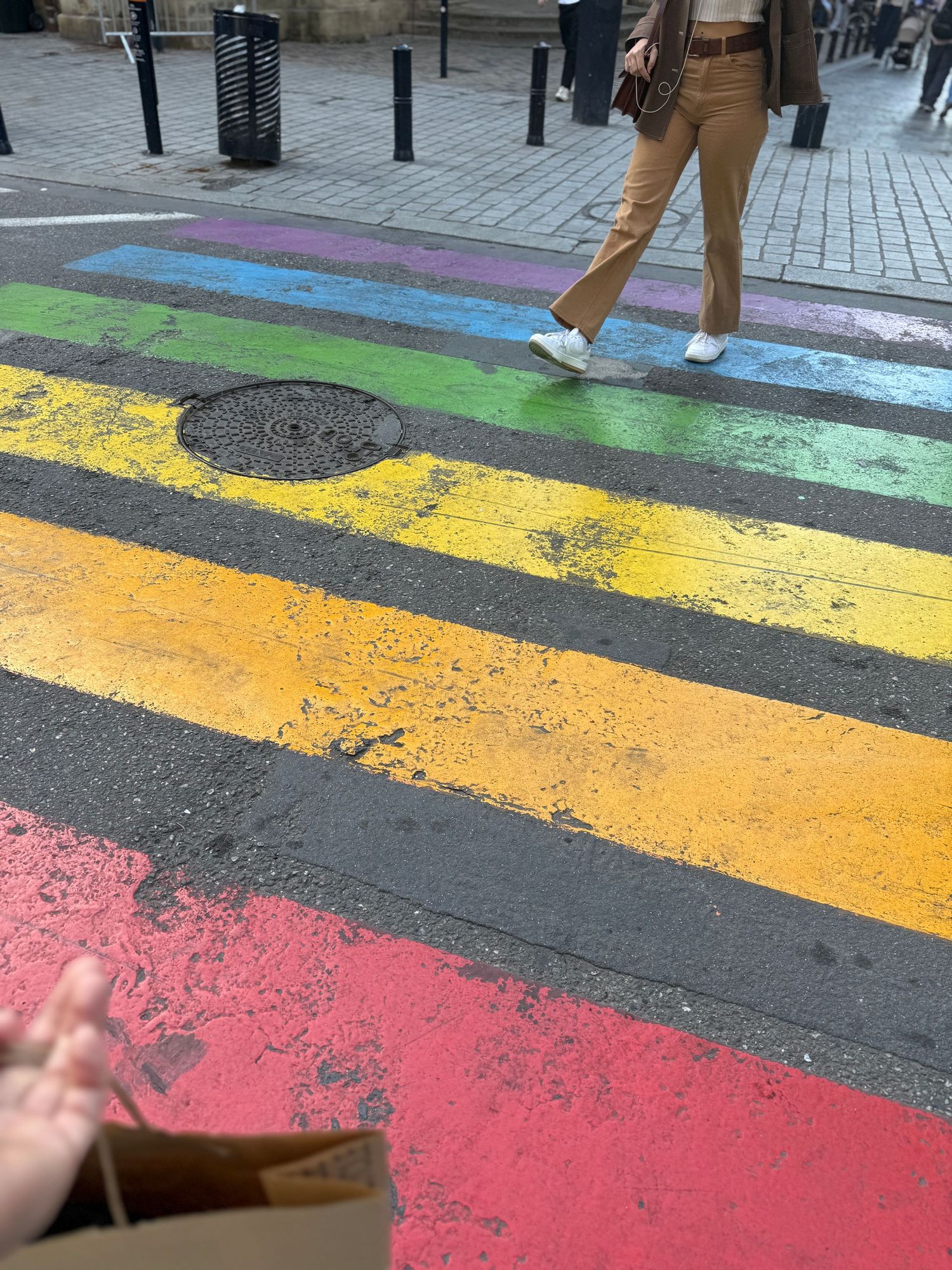 Colorful painted stripes on a city sidewalk featuring yellow, pink, and green lines.