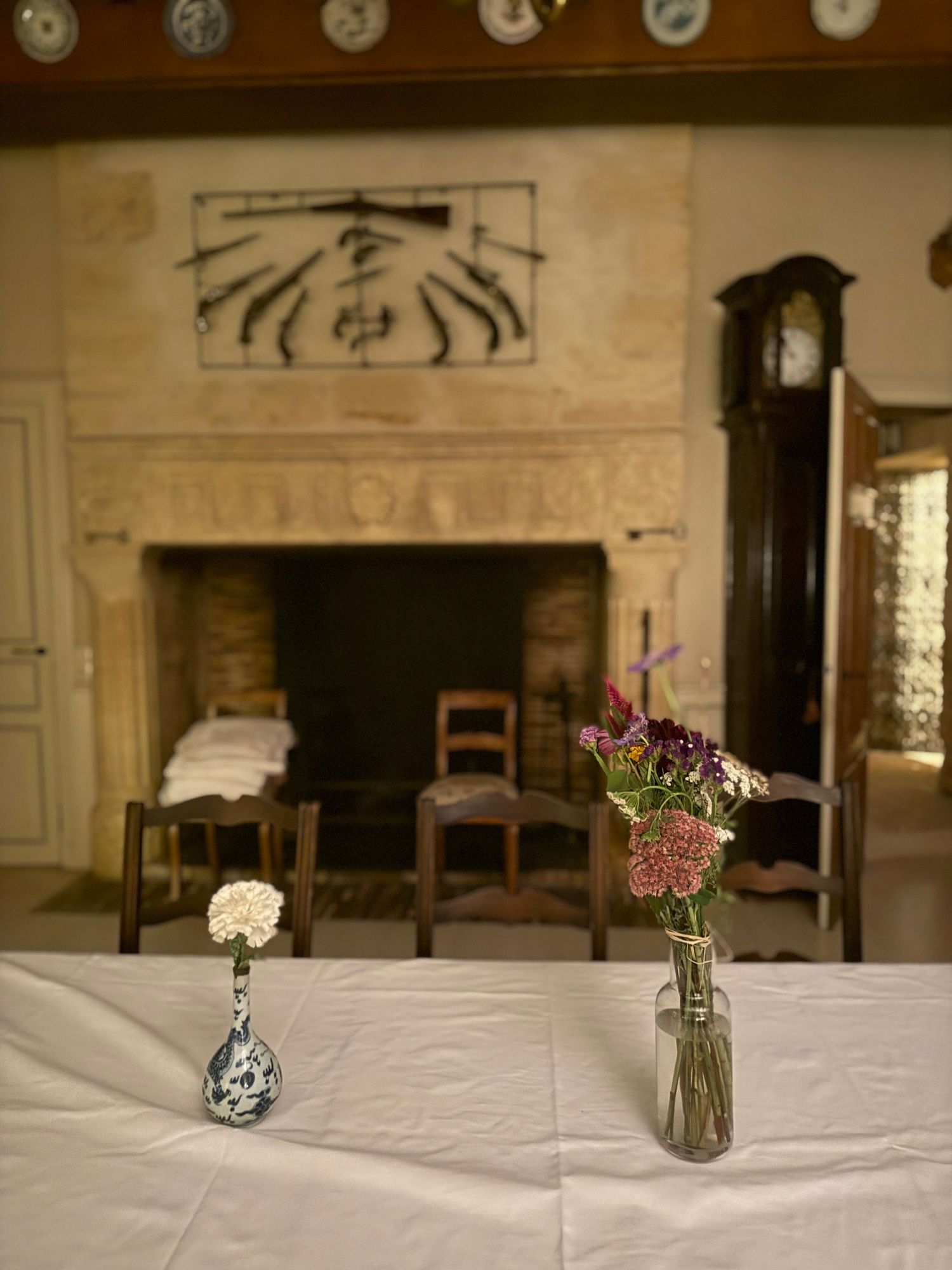 Simple table setting with small flower vases and white tablecloth in rustic room.