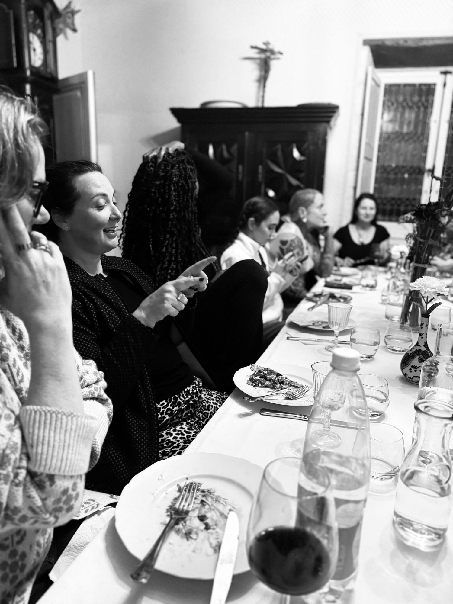 Black and white photo of dinner party guests enjoying a meal at a long table.