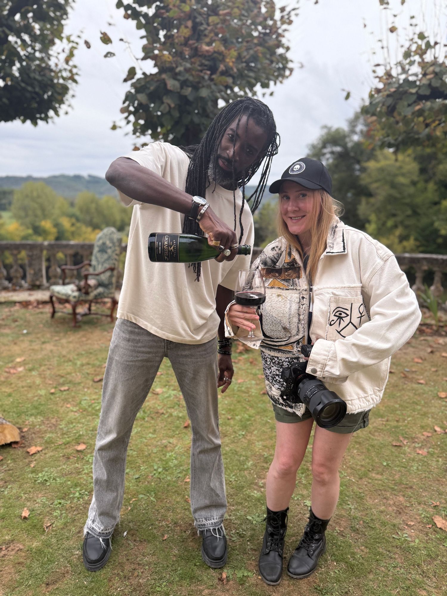 Close-up view of camera equipment and boots on grassy ground during an outdoor photo shoot.