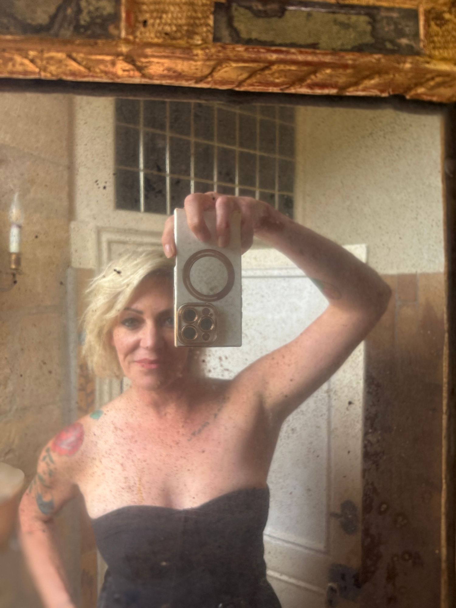 Mirror selfie showing photography equipment in a rustic interior space.