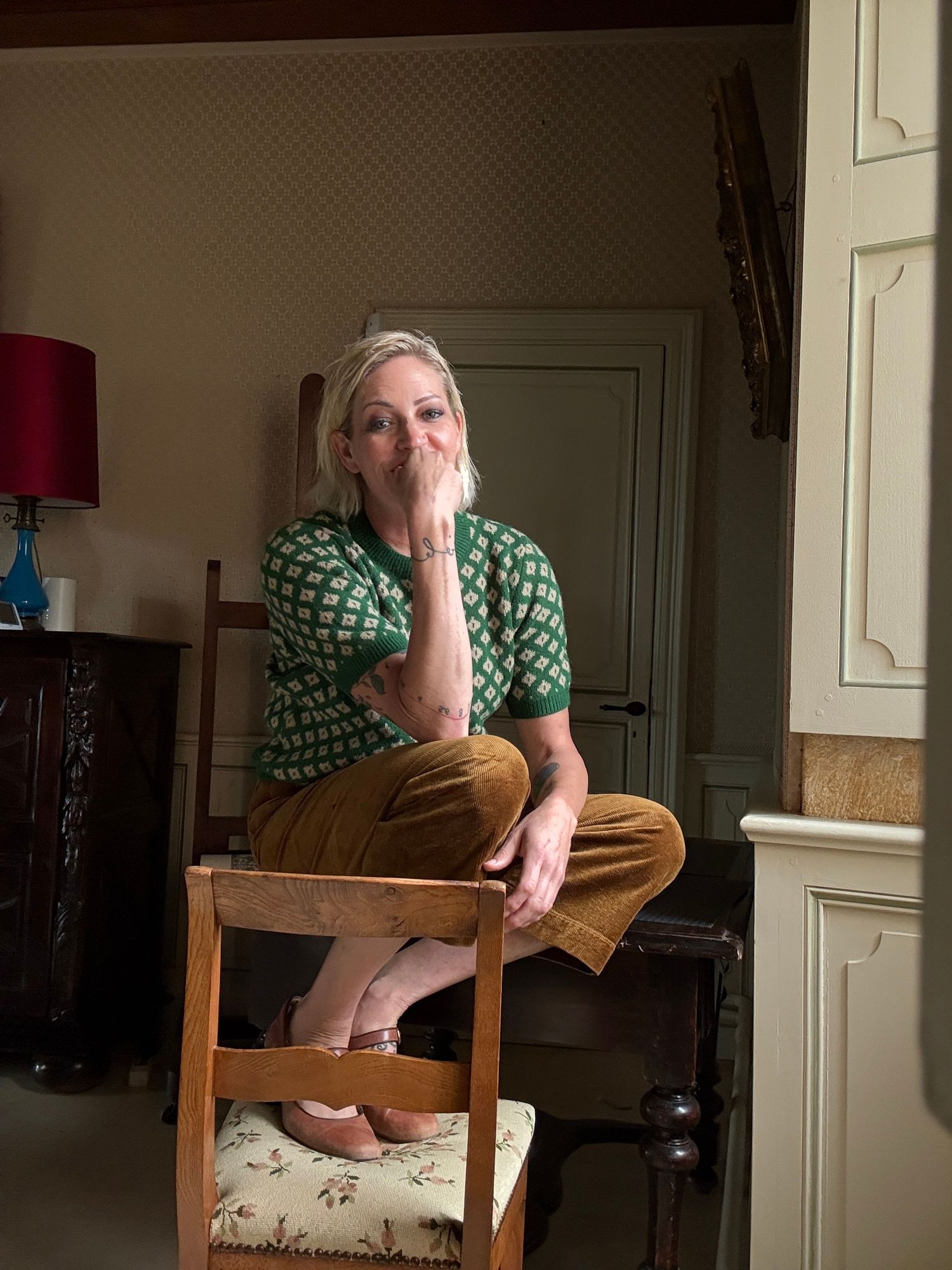 Person sitting on a wooden chair in a room with vintage-style interior decor.